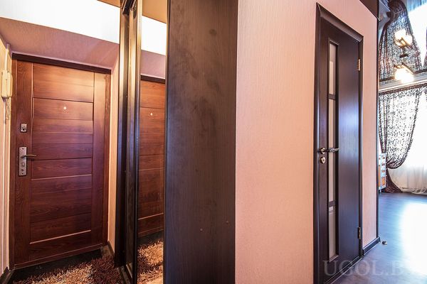 Интерьер прихожей с зеркальной стеной, входной дверью и межкомнатной дверью с матовыми вставками.