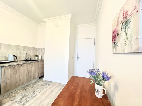 Мойка, чайник и контейнер на фоне плиточного фартука, переход пола от плитки к ламинату, на столе кружка с фиолетовыми цветами.