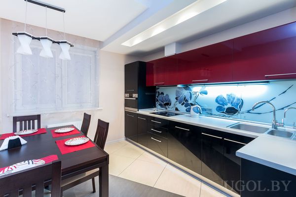 Рабочая зона с плитой, мойкой, фартуком, столом, посудой, светильником и шторами.