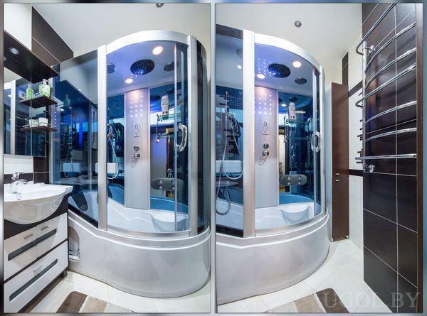 Комната с душем, умывальником, зеркалом, полками, полотенцесушителем и светлой плиткой.