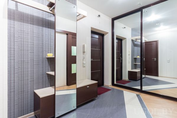 Зона входа с зеркалом, тумбой, полками, плиткой, дверями и декоративной отделкой.