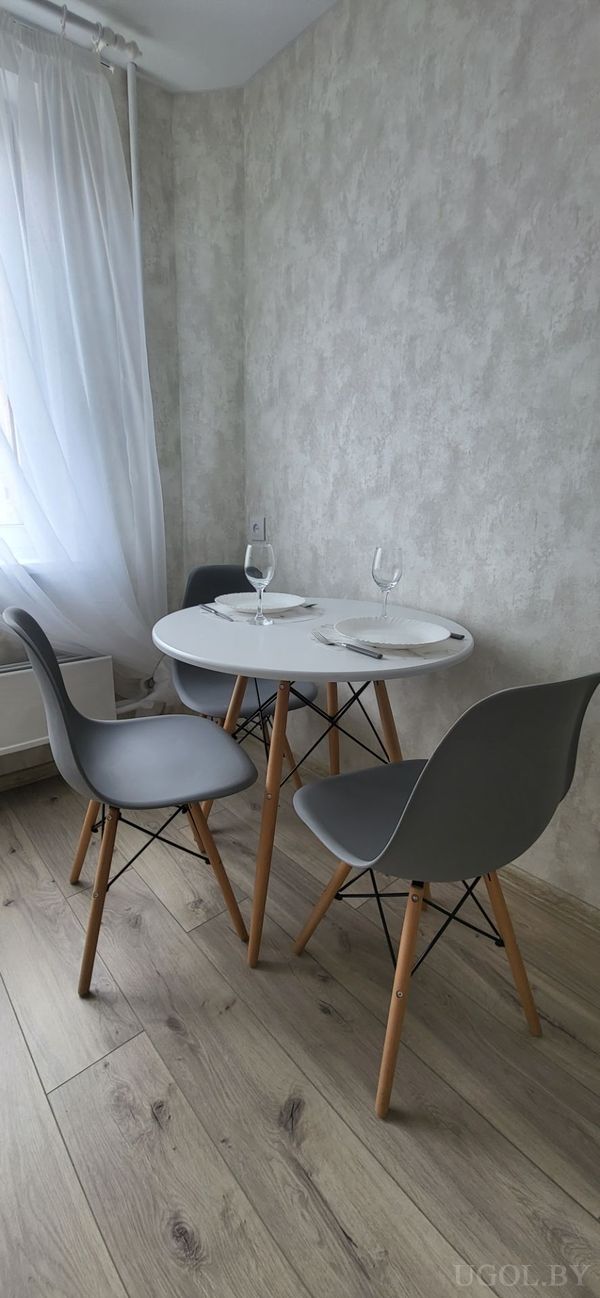 Уголок с круглым столом, серыми стульями, сервировкой на двоих и окнами с тюлем.