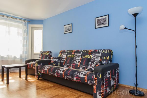 Мебель с графикой, кресло, торшер, чёрный столик, голубые стены и фото в чёрных рамках.