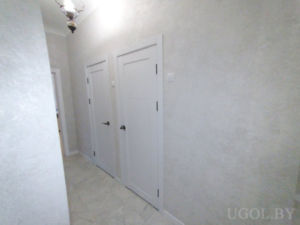 Интерьер с дверями, плиткой, потолочным светильником и фактурной отделкой стен.