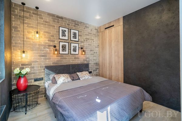 Комната с кроватью, серым текстилем, настенным декором, подвесными светильниками и встроенным шкафом.