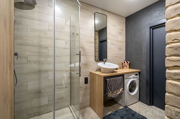 Комната с душевой, умывальником, машиной, кирпичной стеной и тёмной дверью.