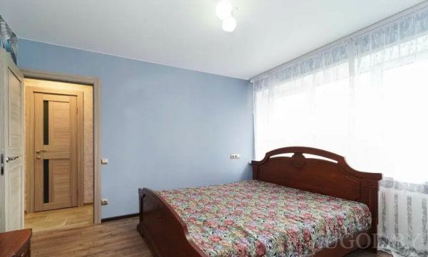 Комната с деревянной мебелью, большим окном и светлым интерьером.