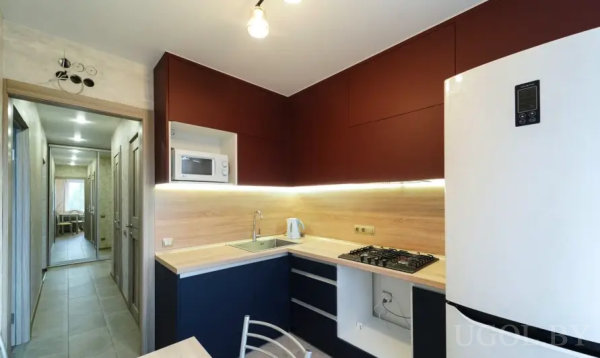 Компактная кухня с микроволновкой, плитой и белым холодильником.