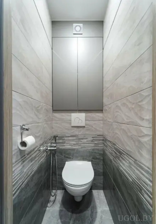 Компактная ванная с серыми плитками, гигиеническим душем и вытяжкой.