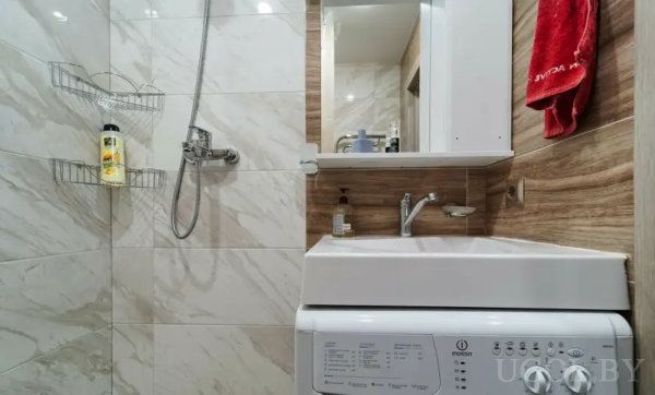 Интерьер с мраморными плитками, зеркальным шкафом и техникой «Indesit».