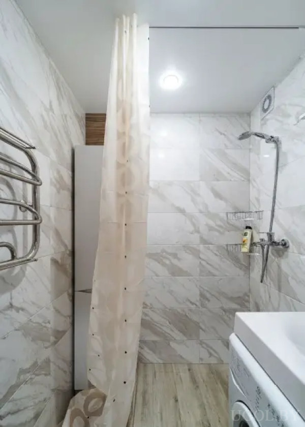 Маленькая ванная с полотенцесушителем, стиральной машиной и светлым потолком.