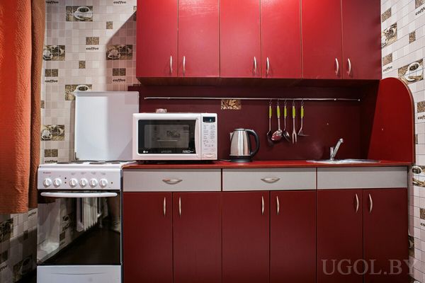 Красные фасады, газовая плита, микроволновка и плитка с кофейной тематикой, компактная и функциональная планировка.