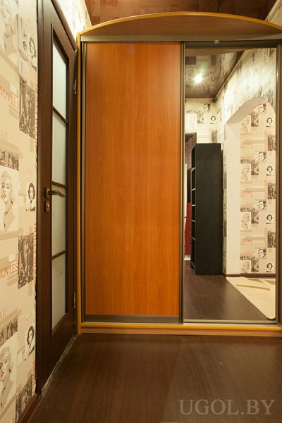 Шкаф-купе с зеркалом, деревянная дверь, винтажные обои и отражение соседней комнаты, тёплый свет и фактурный потолок.