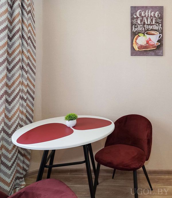 Уютный уголок с белым столом, бордовыми стульями, зелёным растением и постером «Coffee CAKE better together».