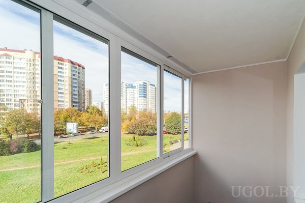 Панорамный вид с лоджии на жилые дома, деревья с жёлтой листвой и дорожки между зелёными газонами.