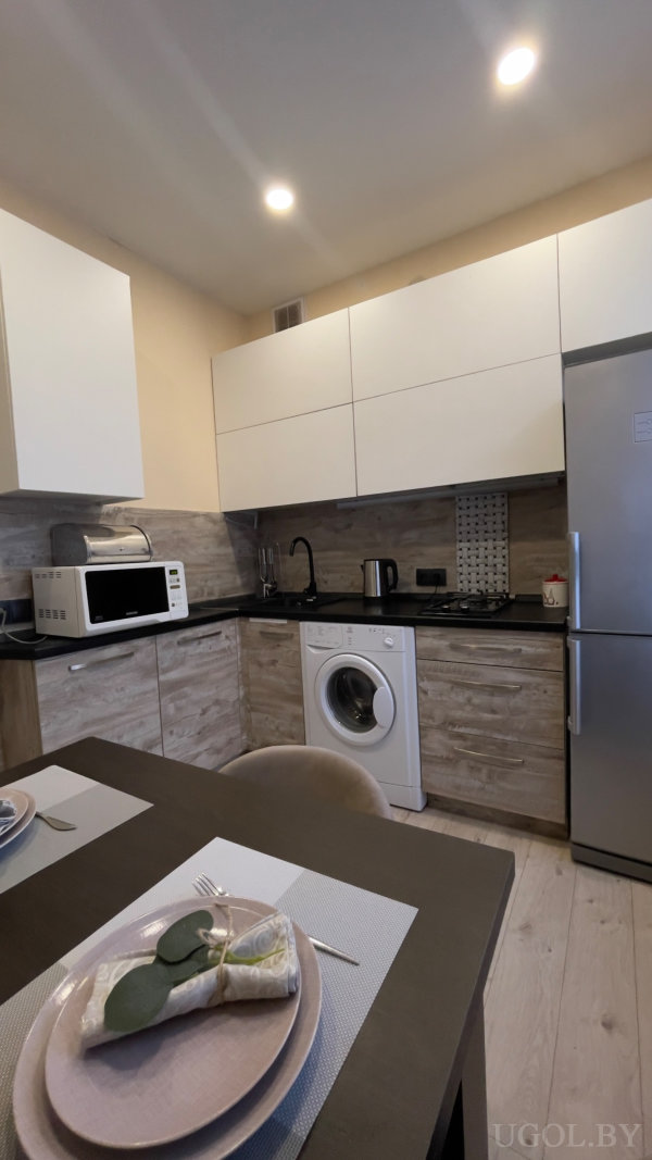 Газовая плита, бело-деревянные фасады, сервировка на столе, холодильник и декоративный фартук.