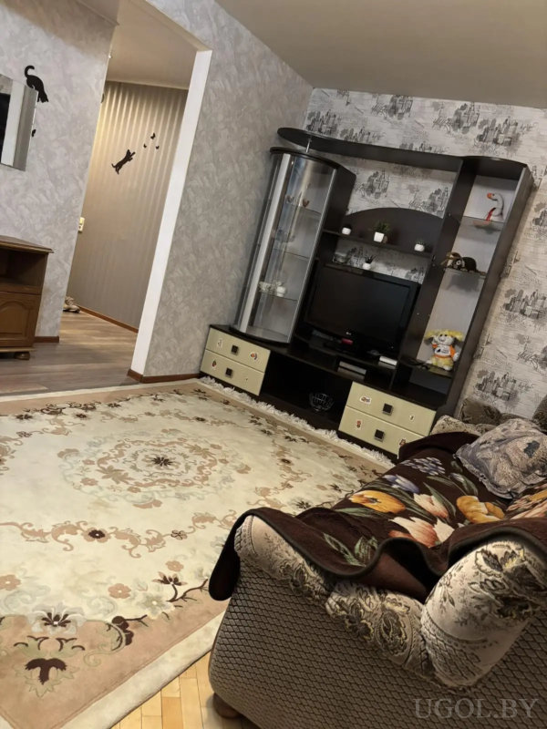 Диван с цветочной обивкой, ковёр, стенка с ТВ, обои с городом, наклейки в коридоре.