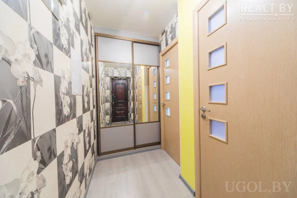 Светлый ламинат, черно-белые обои, желтая акцентная стена и шкаф-купе с зеркалом напротив входной двери.