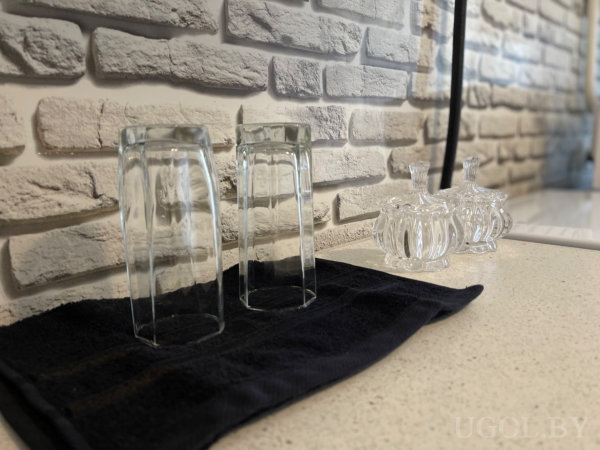 Два бокала на ткани, стеклянные банки с крышками, белый кирпичный фон.