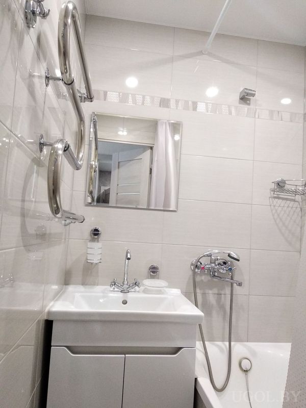 Компактная ванная с белой ванной, раковиной на тумбе, зеркалом и хромированными полотенцесушителями.