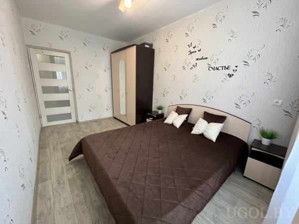 Минималистичный интерьер с зеркальным шкафом, белой дверью и оформлением стены с бабочками и текстом.