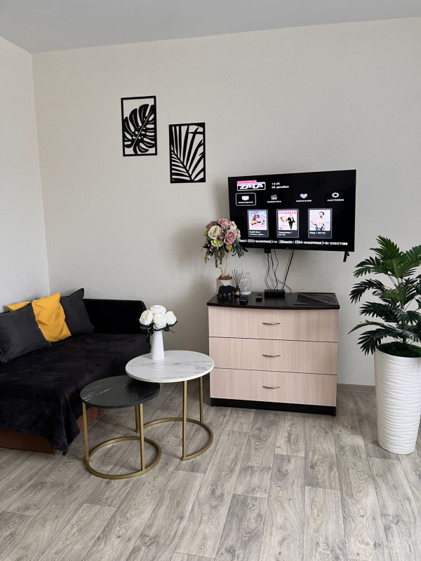 Современный интерьер с мраморными столиками, телевизором и декором на комоде.