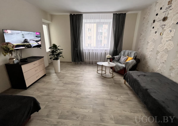 Интерьер с серым креслом, телевизором и настенной композицией с названиями городов.