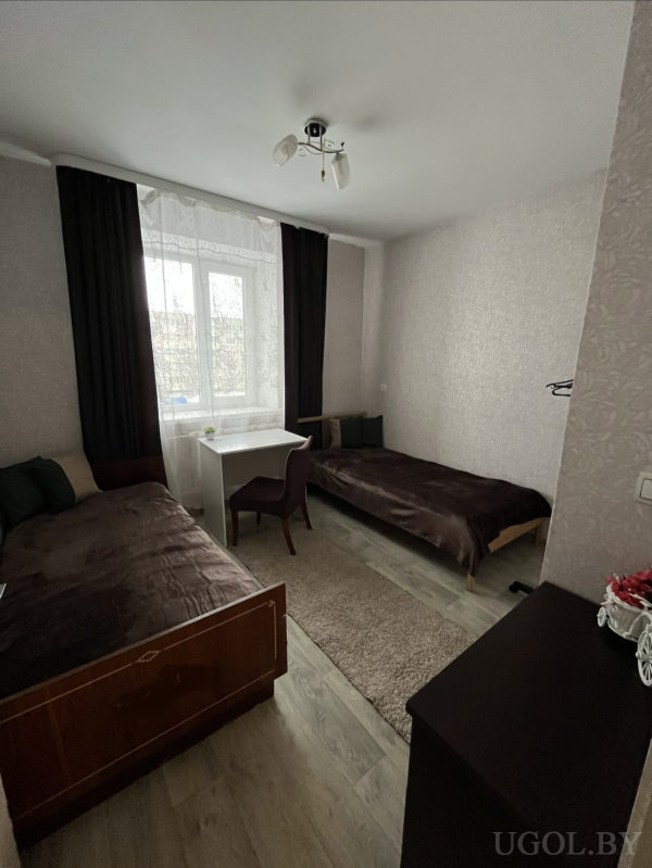 Комната с письменным столом у окна, светлым полом и аккуратным оформлением.