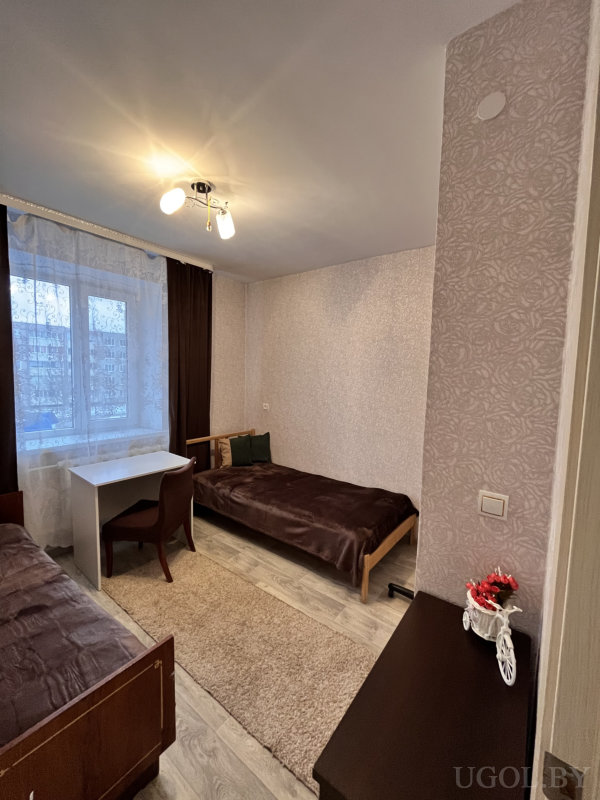 Комната с двумя кроватями, растениями и теплым освещением.