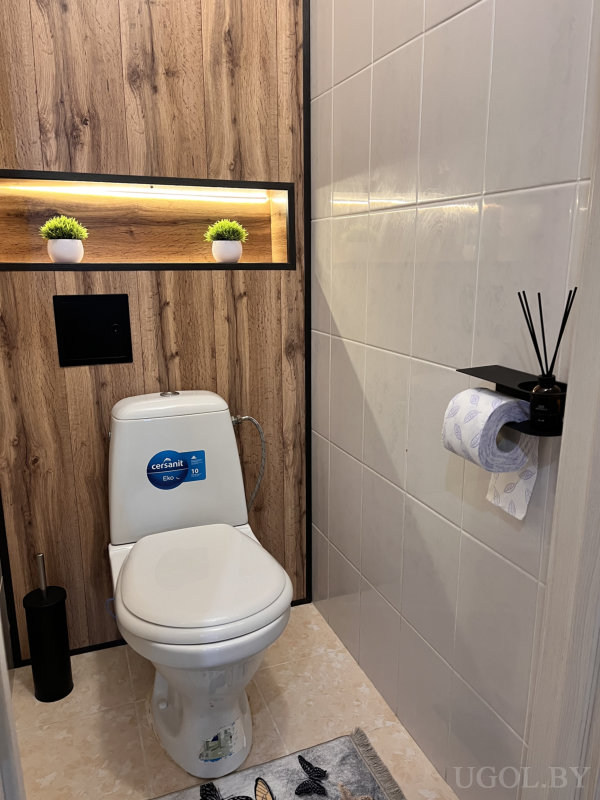 Комната с деревянной панелью, черными аксессуарами и ковриком с бабочками.