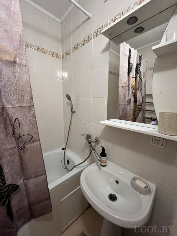 Чистая ванная с душем, зеркалом с подсветкой и занавеской с бабочками.