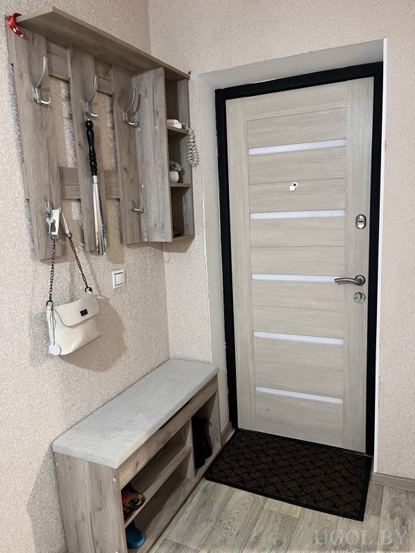 Функциональный уголок с дверью, вешалкой, сумкой и зонтом, оформленный в светлых тонах.