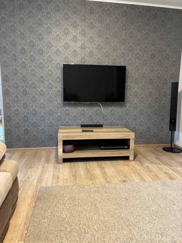 Минималистичный интерьер с телевизором, колонкой и аккуратно организованной техникой.