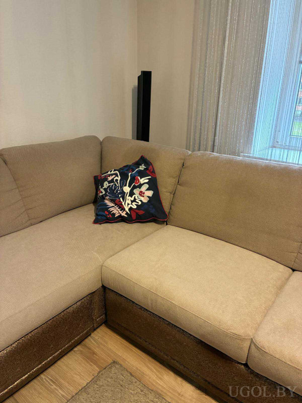 Лаконичный интерьер с яркой подушкой на фоне нейтральных тонов и чёрной колонкой.