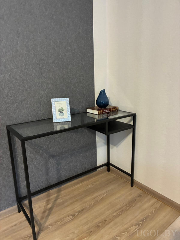 Металлический стол с книгами, синим керамическим декором и ботанической иллюстрацией.