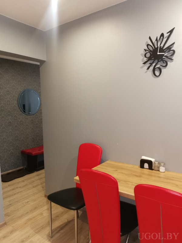 Серый фон, абстрактные часы, три стула и проход в прихожую с зеркалом и банкеткой.