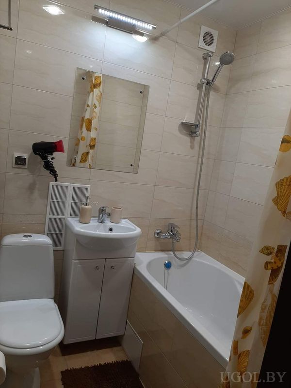 Компактная ванная с унитазом, раковиной, ванной с жёлтой шторой и зеркалом над умывальником.