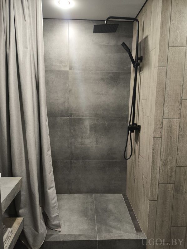 Современная ванная с душем, серой плиткой, деревянной стеной и серой занавеской.