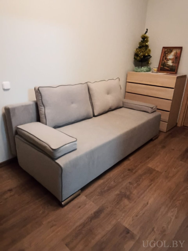 Комната с диваном, комодом, ёлкой, картиной и нейтральной отделкой стен.