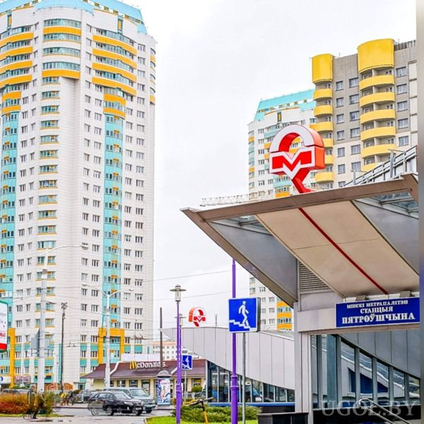 Городская сцена с метро, высотками, рестораном, пешеходными знаками и дневным небом.